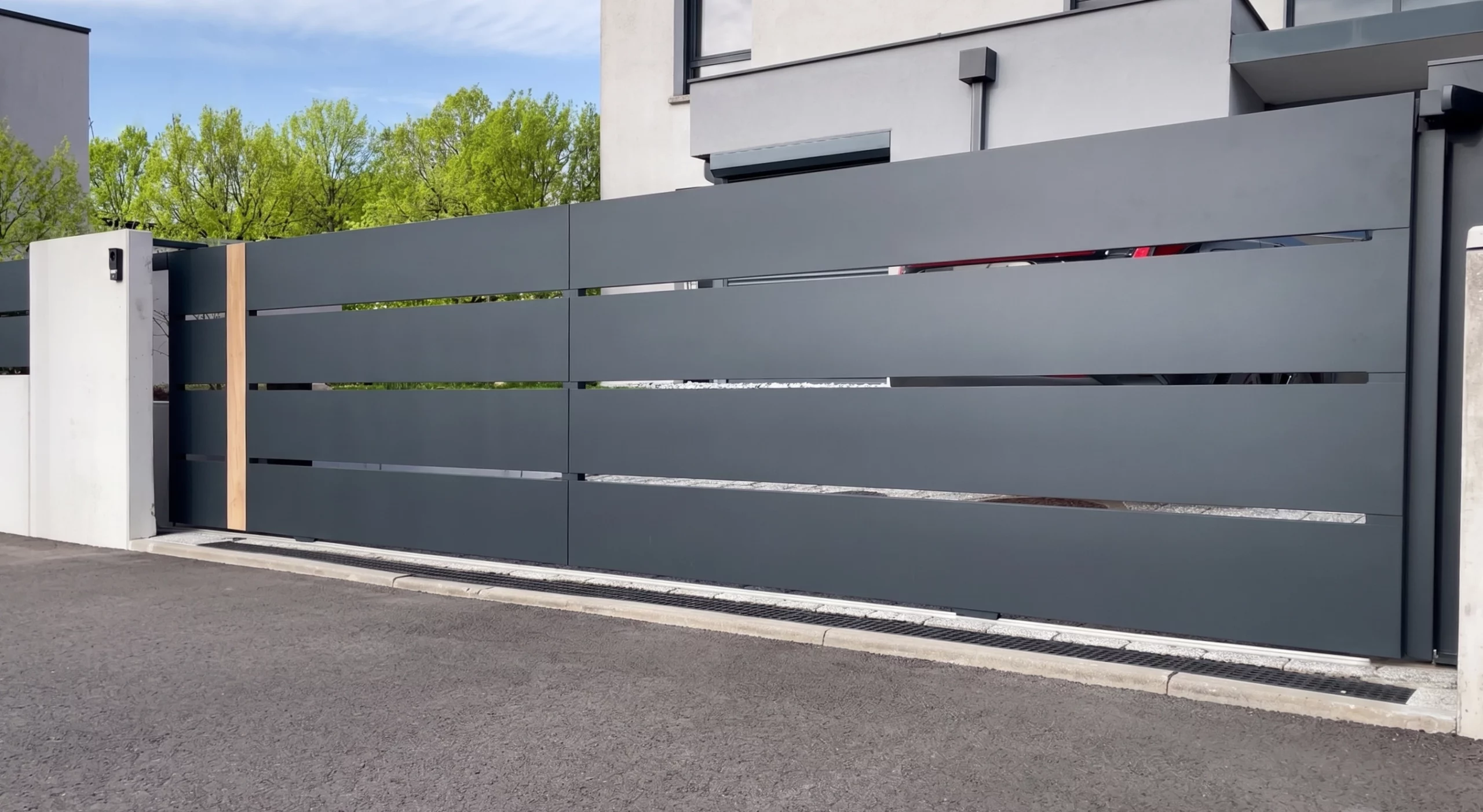Portail en aluminium coulissant en pente SELECT par BREDOK gris anthracite avec frise imitation bois